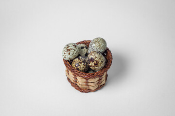 Quail eggs on a white background. Healthy eating. Quail eggs lie in a wicker basket
