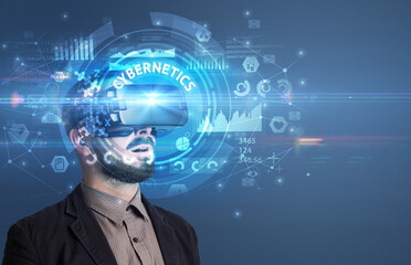 Businessman looking through Virtual Reality glasses with CYBERNETICS inscription, innovative technology concept