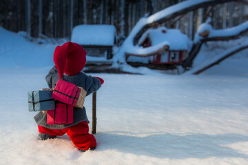 christmas elf carrying presents walking in snow towards snowy toy houses