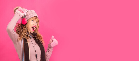 adult woman dancing with headphones and warm clothes isolated on background
