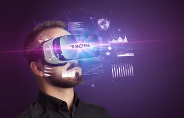 Fototapeta na wymiar Businessman looking through Virtual Reality glasses with FRANCHISE inscription, new business concept