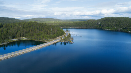 Fototapeta premium Aerial view of the road near the lake and the forest from above. highway with cars besides the lake and forest. 