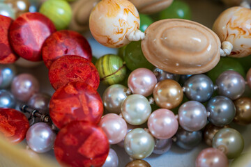Mixed jewellery box including blood orange coral stone bracelet, green grape agate bracelet, multi-colored pearl necklace and cream ceramic necklace
