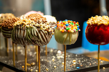 Various candied caramel apples on a stick standing in a street food shop on christmas fair