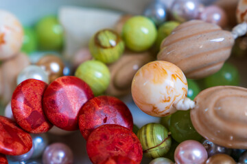 Mixed jewellery box including blood orange coral stone bracelet, green grape agate bracelet, multi-colored pearl necklace and cream ceramic necklace

