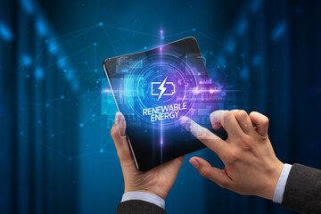 Businessman holding a foldable smartphone with INNOVATIVE inscription, new technology concept RENEWABLE ENERGY