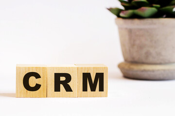 On a light background, wooden cubes with the inscription CRM CRM customer relation management and a...