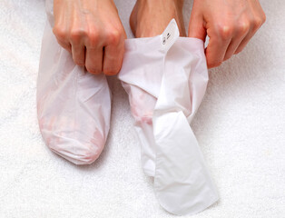 Sock-mask for feet on a female leg, white towel background
