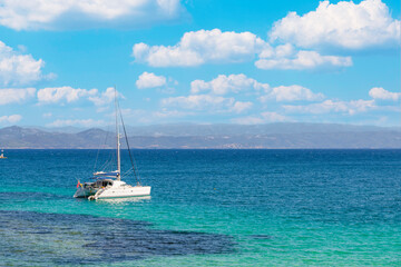 Fototapeta premium Sail boat, yacht in a beautiful bay with blue water during sunny day, Chalkidiki, Greece