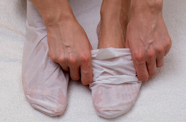 Sock-mask for feet on a female leg, white towel background