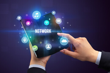Businessman holding a foldable smartphone with NETWORK inscription, social media concept