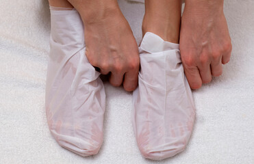 Sock-mask for feet on a female leg, white towel background