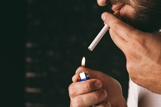 Bearded man lighting cigarette with fire lighter