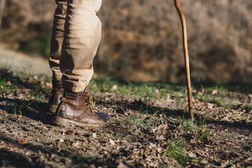 Close-up dirty boots of hiker man walking in a muddy path. Unrecognizable person in outdoors activities.