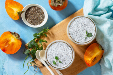 Panna Cotta with persimmon fruit and chia seeds, Italian dessert, home cooking. Top view flat lay background.