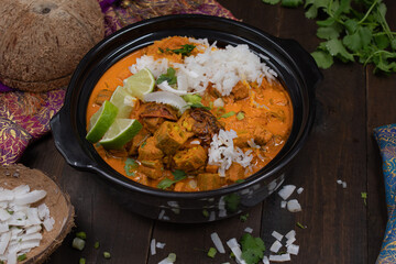Vegan thai red curry with okra and peppers over jasmine rice, in black clay bowl