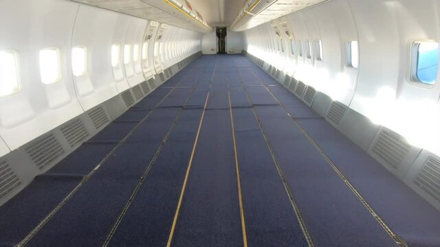 Airplane in-flight - walking through an empty airplane cabin from front to rear. All passenger seats are removed.