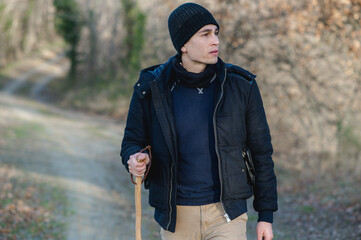 Guy walking with pole in a natural landscape during winter season practicing outdoors activities looking at the camera.