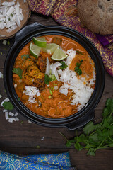 Vegan thai red curry with okra and peppers over jasmine rice, in black clay bowl