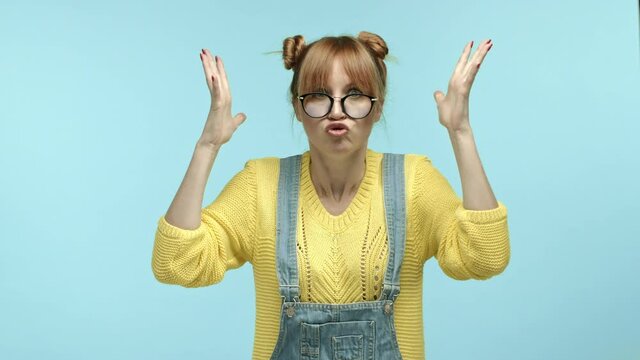 Annoyed and pressured hipster girl showing head explosion gesture, boiling with anger and looking tensed, standing over blue background