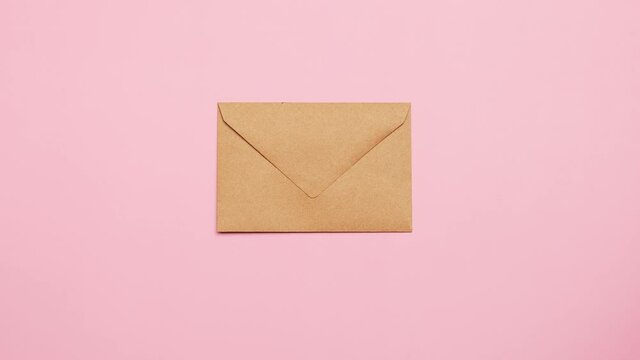 Hand delivery craft paper mail envelope for letters on a pink background. Minimalist style, top view, correspondence concept.