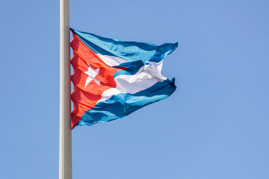 Flag of the Republic of Cuba, an island nation in Latin America, against a blue sky background.