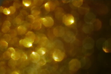 Obraz premium Golden bokeh background with soft light and circular reflections. Warm abstract texture ideal for festive themes, celebration, luxury, or elegant design elements