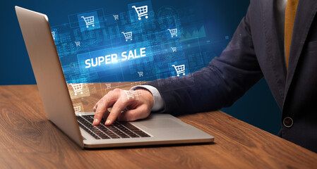 Businessman working on laptop with SUPER SALE inscription, online shopping concept