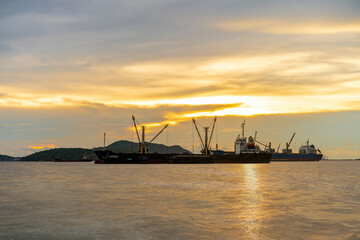 Large cargo ship for logistic import export goods anchor at sea in evening with golden sunset