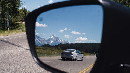 Fototapeta na wymiar large mountains through a car side mirror