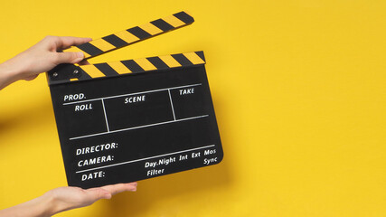Fototapeta na wymiar Hand is holding clapper board or movie slate.It is used in film production and cinema,movies industry on yellow background.