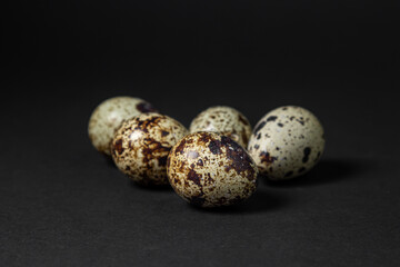 Obraz premium Quail eggs on a black background. Healthy food. Several quail eggs lie next to each other