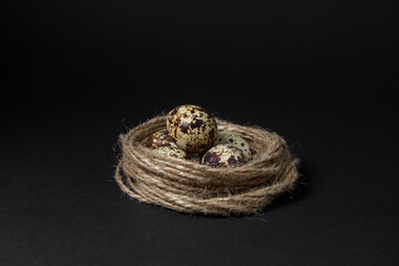 Quail eggs on a black background. Healthy food. Quail eggs lie in a nest made of jute thread