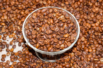 Roasted coffee beans are scattered on the surface and poured into a glass vase that stands in the middle.