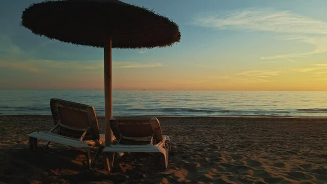 Cinemagraph loop of parasol and chairs on the beach at dusk