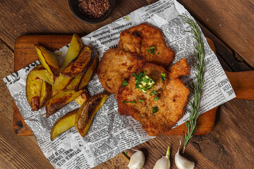A top view of delicious schnitzel and potatoes served on a wooden board