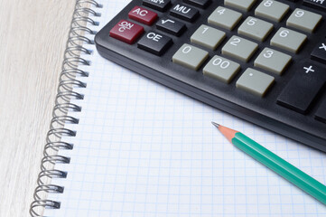 calculator, notebook and pencil lie together. close-up.