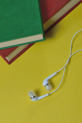 white small headphones and stack of books audiobook concept.