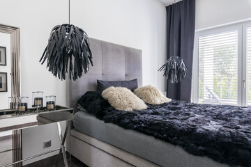 Elegant grey bed with black bedding in bright room interior