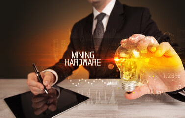 Businessman holding lightbulb with MINING HARDWARE inscription, Business technology concept