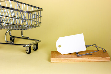 Supermarket trolley and mousetrap with blank tag on yellow background. Place for the text. Sly...