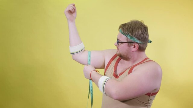 Funny fat man in sportswear measures his hand with centime