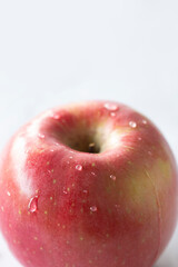 Manzana roja con gotas de agua sobre fondo vertical blanco
