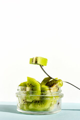 Sliced Kiwi fruits with fork in a glass bowl on turquoise pastel color background. Concept of healthy and diet food.
