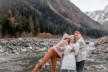 Group of kids hugging and walking outdoor in the nature against the river and beautiful mountains in snow, alpine view