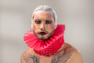 Young actor of theatre with tattoo, stage makeup and hairdo with white hair