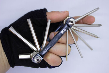 women hand wearing cycling glove holding a multi tool allen set or hex set used for bicycle repair closeup, white background and top view.space for text.