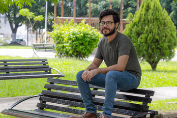 Obraz premium man with beard and glasses sitting on bench in park