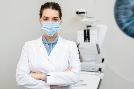 Young Brunette Female Ophthalmologist In Protective Mask And Whitecoat