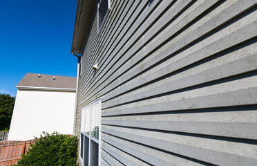 Vinyl siding on exterior of home with dirt and weathering.